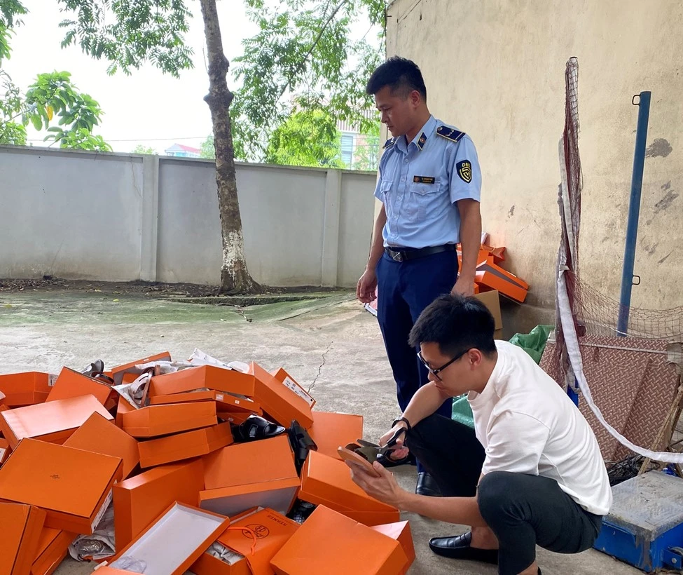 Lực lượng chức năng kiểm tra hàng hóa có dấu hiệu giả mạo nhãn hiệu HERMÈS. (Ảnh: PV/Vietnam+)