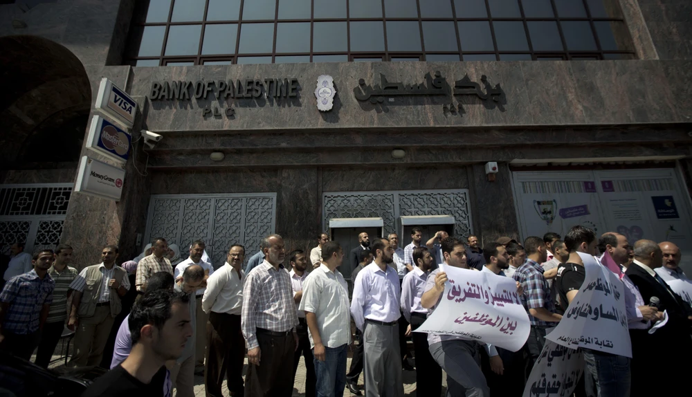 Viên chức Palestine xếp hàng yêu cầu được nhận lương bên ngoài Ngân hàng Palestine ở thành phố Gaza. (Nguồn: AFP/TTXVN) 