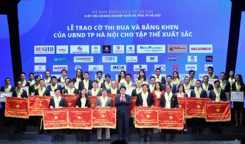 Chủ tịch Ủy ban Nhân dân thành phố Hà Nội Nguyễn Đức Chung trao bằng khen của thành phố cho các doanh nghiệp đạt thành tích xuất sắc. (Ảnh: Danh Lam/TTXVN) 
