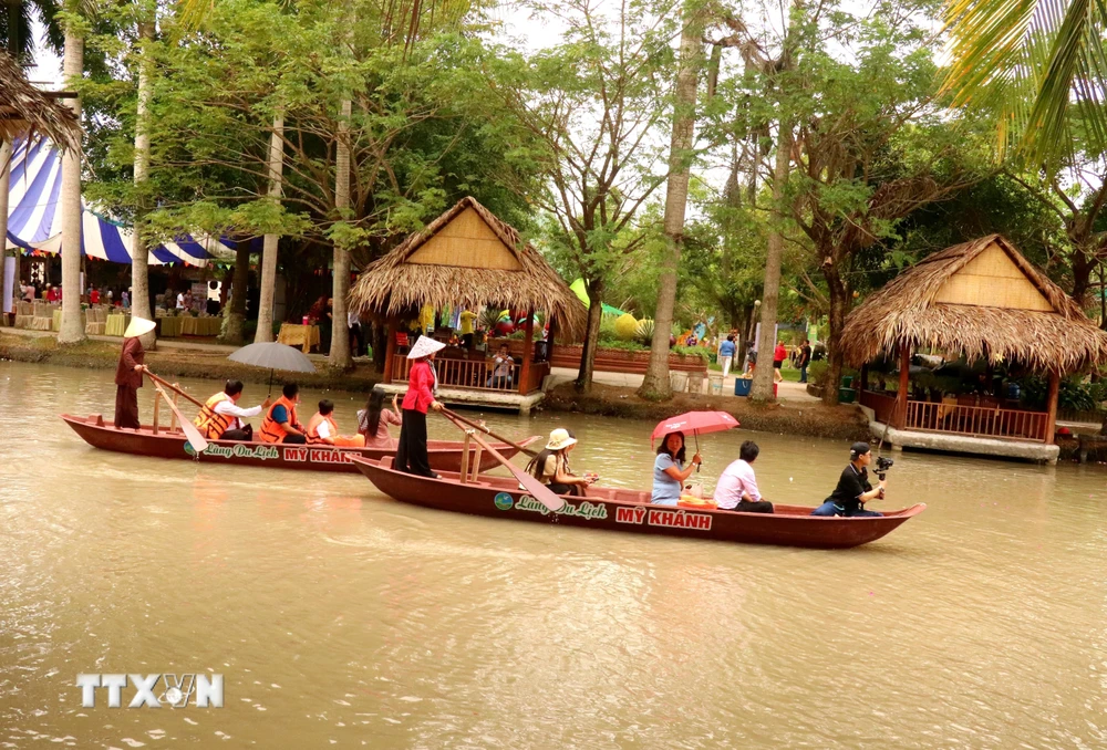 Du khách trải nghiệm chèo thuyền trên sông ở Làng du lịch Mỹ Khánh. (Ảnh: Thu Hiền/TTXVN)