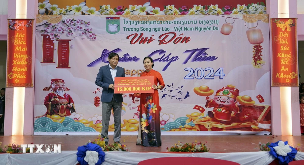 Đại sứ Việt Nam tại Lào Nguyễn Bá Hùng trao quà cho đại diện nhà trường. (Ảnh: Bá Thành/TTXVN)