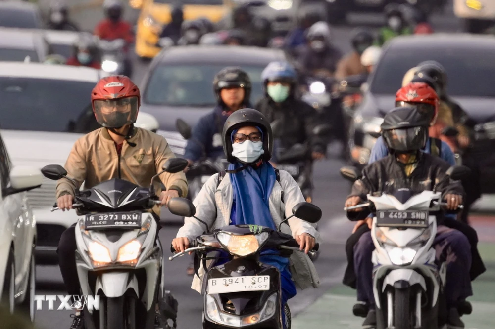 Người dân đeo khẩu trang tránh khói bụi trên một tuyến đường ở Jakarta, Indonesia. (Ảnh: AFP/TTXVN)