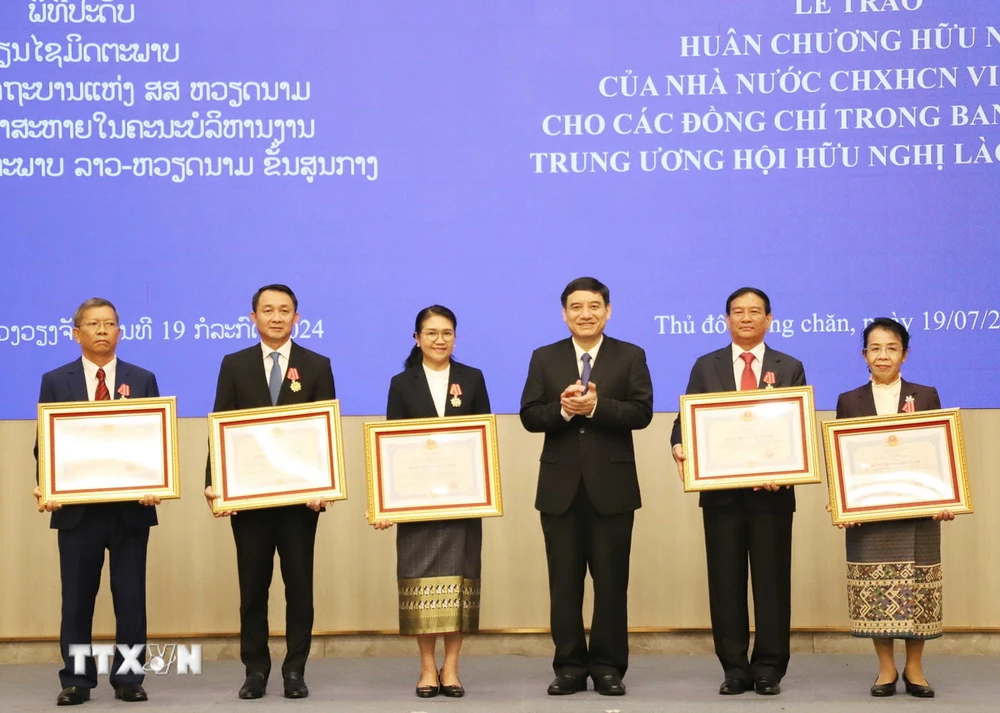 Chủ tịch Trung ương Hội Hữu nghị Việt Nam-Lào Nguyễn Đắc Vinh trao tặng Huân chương Hữu nghị của Nhà nước Việt Nam cho các thành viên của Trung ương Hội Hữu nghị Lào-Việt Nam. (Ảnh: Xuân Tú/TTXVN)