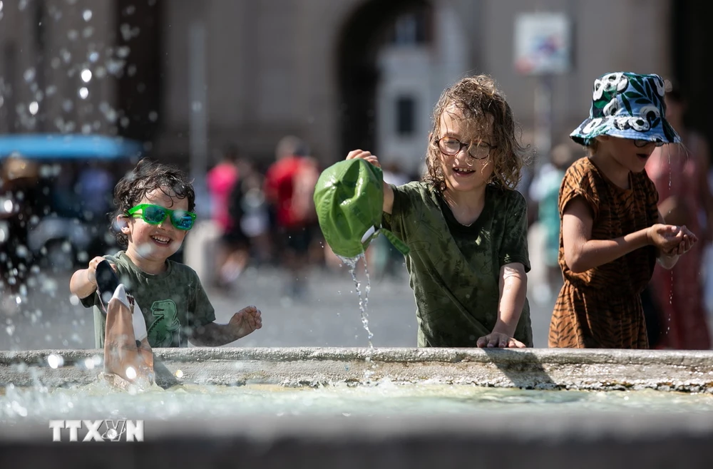 Trẻ em làm mát bên đài phun nước trong ngày nắng nóng ở Rome, Italy, ngày 14/7/2024. (Ảnh: THX/TTXVN)