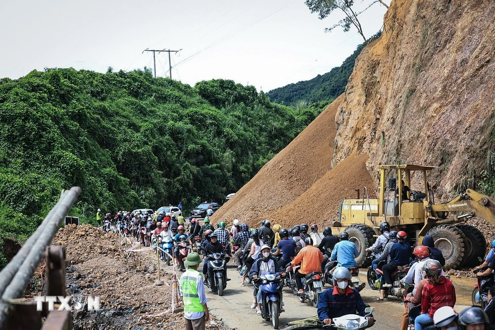 Người và phương tiện giao thông di chuyển chậm nối nhau đi qua điểm sạt lở tại dốc Cun, Km79+335, Quốc lộ 6, thuộc địa phận phường Thống Nhất, thành phố Hòa Bình. (Ảnh: Trọng Đạt/TTXVN)