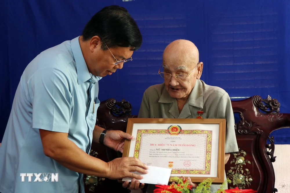 Ông Nguyễn Tiến Hải trao Huy hiệu 75 năm tuổi Đảng cho đảng viên Vũ Minh Chiếu. (Ảnh: Kim Há/TTXVN)