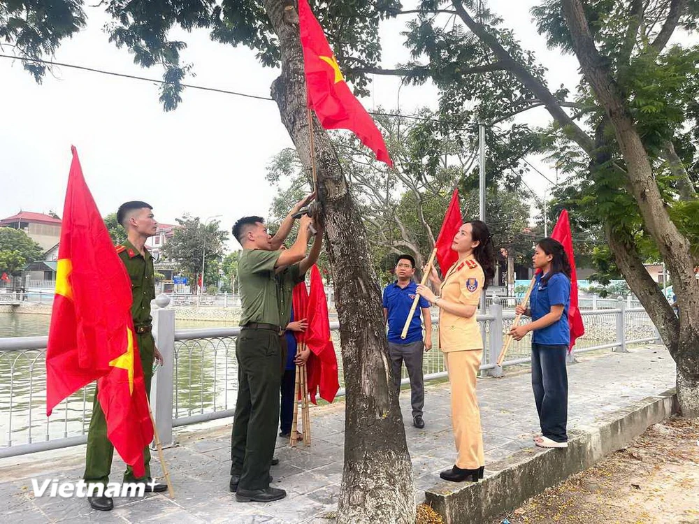 Đoàn viên thanh niên treo cờ Tổ quốc và cờ Đảng xung quanh hồ Mai Trai, xã Vạn Thắng, huyện Ba Vì. (Ảnh: Mạnh Khánh/TTXVN)