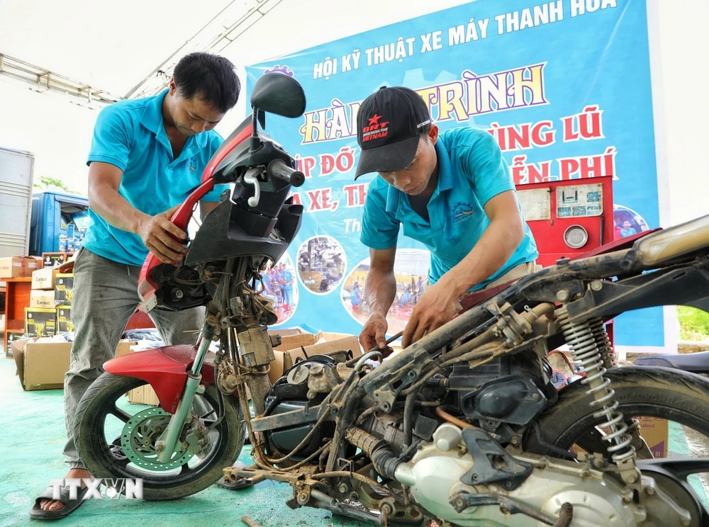 Những người thợ sửa xe máy của Hội kỹ thuật xe máy Thanh Hóa sửa xe cho người dân tại địa điểm Nhà văn hóa tổ 13, phường Yên Ninh trong sáng 18/9. (Ảnh: Tuấn Anh/TTXVN)