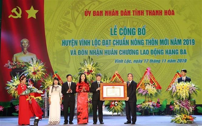 Đồng chí Nguyễn Văn Bình Trưởng ban Kinh tế Trung ương trao Bằng công nhân huyện Vĩnh Lộc đạt chuẩn huyện nông thôn mới năm 2019. (Ảnh: Duy Hưng/TTXVN)