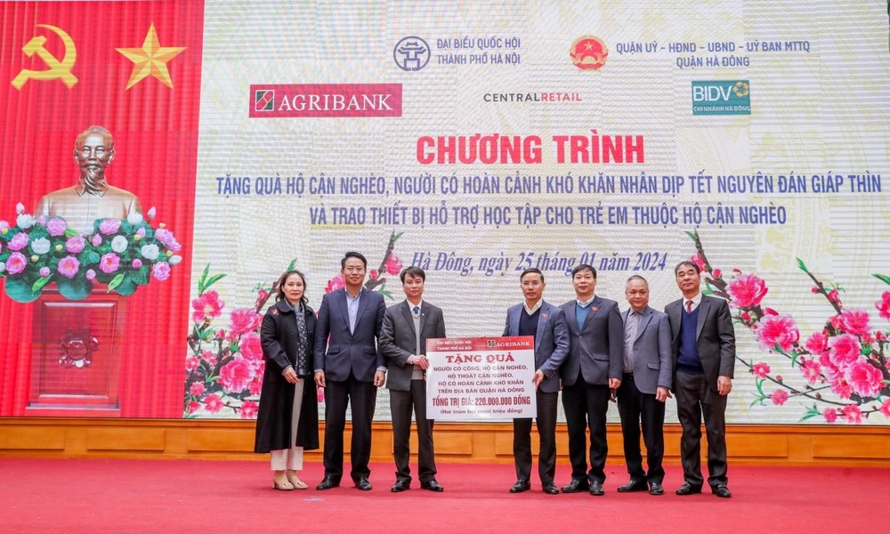 Ông Phạm Đức Ấn - Chủ tịch Hội đồng thành viên Agribank trao tặng quà của Agribank hỗ trợ hộ cận nghèo, đối tượng chính sách quận Hà Đông (Hà Nội) nhân dịp Tết Nguyên đán Giáp Thìn. (Ảnh: PV/Vietnam+)