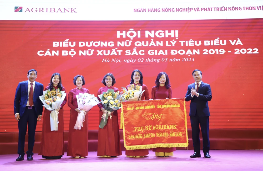 Đảng ủy - Hội đồng thành viên - Ban điều hành Agribank trao tặng Phụ nữ Agribank 8 chữ vàng: Năng động – Sáng tạo – Nhân hậu – Đảm đang. (Ảnh: Vietnam+)
