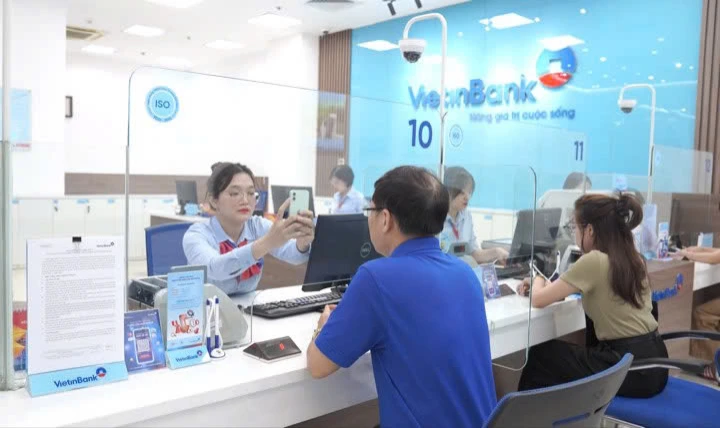 Cán bộ VietinBank hướng dẫn khách hàng xác thực sinh trắc học. (Ảnh: Vietnam+)