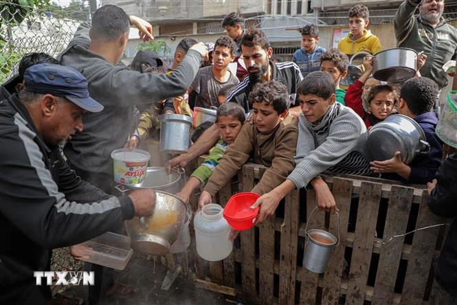 Người dân nhận thức ăn cứu trợ tại thành phố Rafah, Dải Gaza. (Ảnh: THX/TTXVN)
