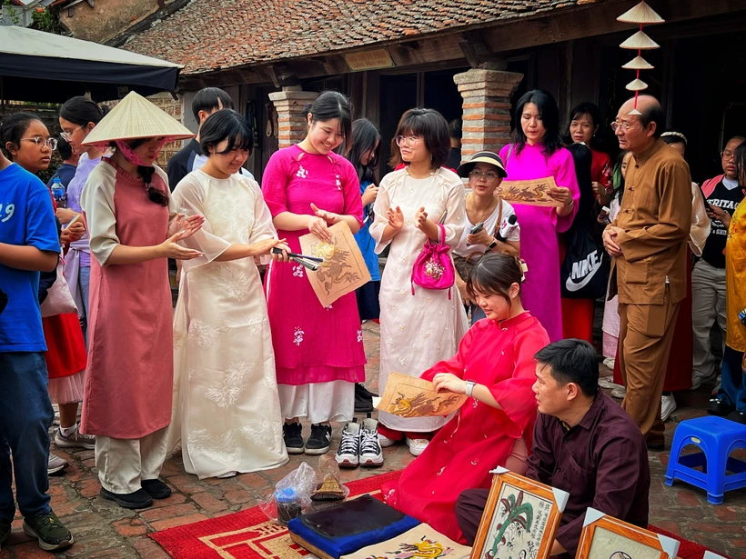 Du khách Hàn Quốc trải nghiệm làm tranh Đông Hồ ở Hà Nội. (Ảnh: Mai Mai/Vietnam+)