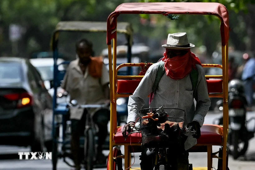 Người dân đội mũ và khăn để tránh nắng nóng tại New Delhi, Ấn Độ. (Ảnh: AFP/TTXVN)