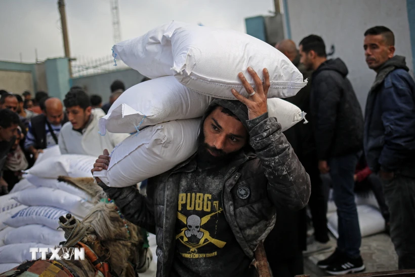 Người dân nhận hàng viện trợ nhận đạo tại trung tâm phân phối của UNRWA ở thành phố Rafah, Dải Gaza. Ảnh: AFP/TTXVN