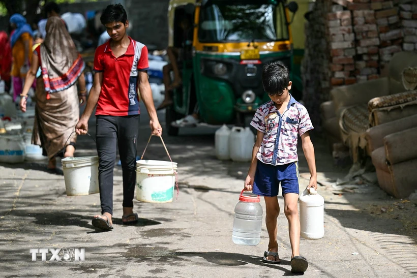 Các em nhỏ lấy nước tại điểm cấp nước công cộng ở New Delhi, Ấn Độ. (Ảnh: AFP/TTXVN)