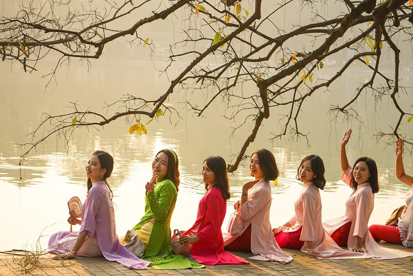 Các thiếu nữ Hà Nội dịu dàng trong trang phục áo dài bên Hồ Hoàn Kiếm. (Ảnh: Khánh Hoà/TTXVN)