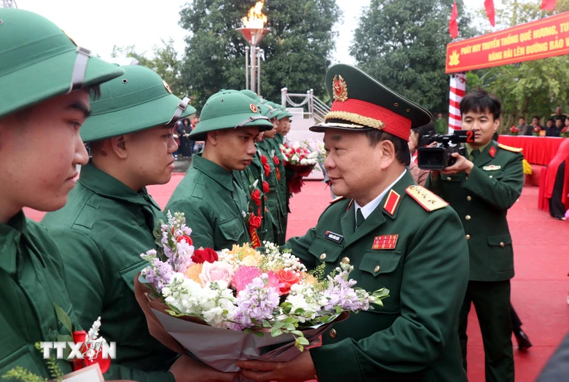 Thượng tướng Hoàng Xuân Chiến, Thứ trưởng Bộ Quốc phòng tặng hoa tân binh lên đường nhập ngũ tại huyện Kim Động, tỉnh Hưng Yên. (Ảnh: Đinh Văn Nhiều/TTXVN)