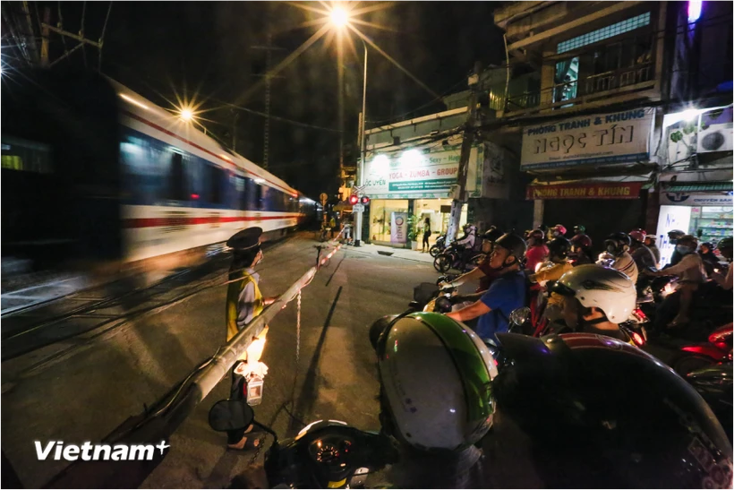 Đoàn tàu chạy qua một đường ngang có chốt trực của nhân viên gác chắn đường sắt. (Ảnh: Minh Sơn/Vietnam+)