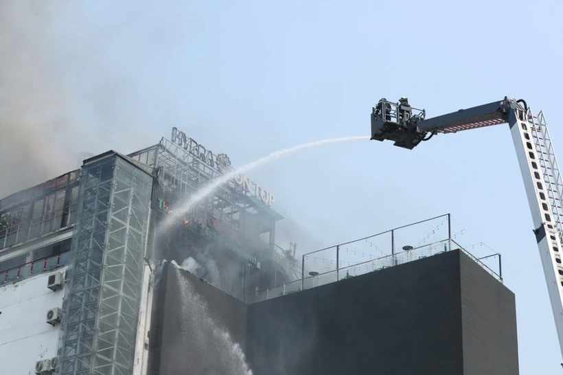 Lực lượng PCCC phải dùng thang cẩu để dập đám cháy trên nhà cao tầng ở ngã bảy Ô Chợ Dừa, quận Đống Đa, Hà Nội sáng 12/3. (Ảnh: Hoàng Hiếu/TTXVN)