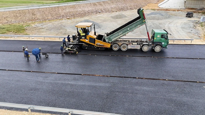 Nhà thầu Tổng Công ty Vinaconex thi công thảm bêtông nhựa mặt đường tại nút giao quốc lộ 8A, xã Thanh Bình Thịnh, huyện Đức Thọ. (Ảnh: Hữu Quyết/TTXVN)