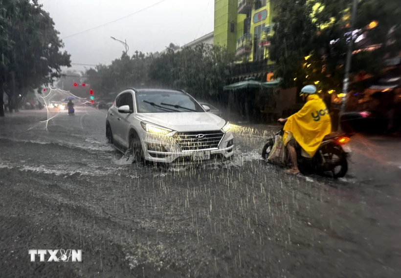 Người và phương tiện gặp nhiều khó khăn khi lưu thông qua các tuyến đường tại thành phố Đồng Hới (Quảng Bình) bị ngập sâu. (Ảnh: TTXVN phát)