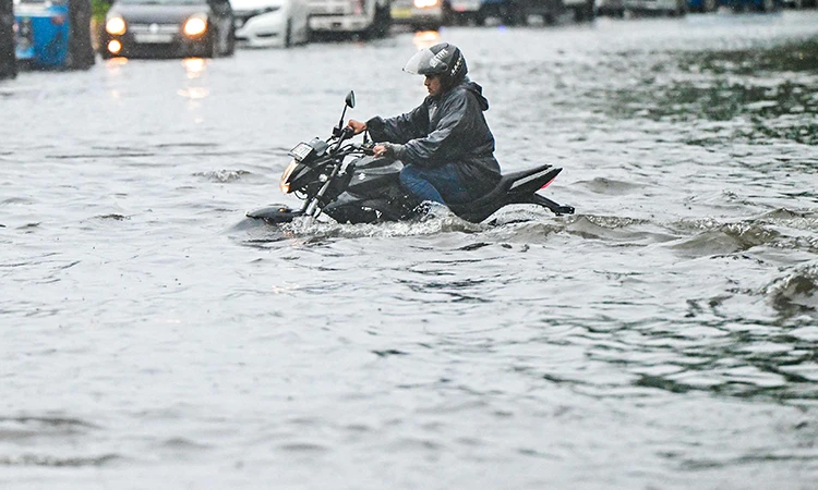 Một người đàn ông lái xe máy qua đường ngập nước sau trận mưa lớn ở thủ đô Colombo, Sri Lanka. (Nguồn: AFP)