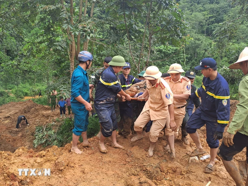 Các lực lượng tìm kiếm đưa thi thể nạn nhân bị vùi lấp ra khỏi khu vực sạt lở. (Ảnh: Đức Thọ/TTXVN)