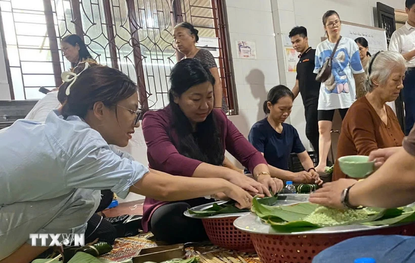 Chủ tịch Ủy ban MTTQ Việt Nam thành phố Hà Nội Nguyễn Lan Hương gói bánh chưng với người dân để chuyển đến những nơi bị lũ lụt. (Ảnh: TTXVN phát)