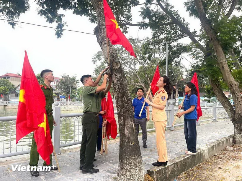 Mitglieder der Jugendunion hängen Nationalflaggen und Parteiflaggen rund um den Mai Trai-See, Gemeinde Van Thang, Bezirk Ba ​​Vi auf. (Foto: Manh Khanh/VNA)